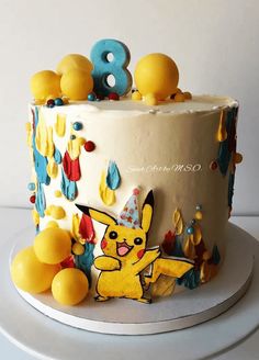 a birthday cake decorated with pikachu and balloons