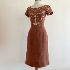 Vintage 1960s wiggle sheath dress in russet brown has an intricate embroidered cutwork bodice with cap sleeves and a wide neckline that's lower in the back, and a fitted skirt with scattered embroidered flowers. Fabric is a soft textured woven that feels like rayon. Back metal zip.  In beautiful vintage condition with a few loose threads and one break in the lace on the left sleeve as shown. Looks like an XS/S; shown on a 34-24-35 dress form with a bit of wiggle room. Laid flat measures 17" across armpits, 13.75" across waist, hip across at bottom of back zip 19", total length from high point of shoulder to hem approx. 41". Fitted Cap Sleeve Lace Dress, Fitted Lace Dress With Cap Sleeves, Cap Sleeve Fitted Lace Dress, Vintage Cap Sleeve Dresses, Brown Fitted Square Neck Dress, Vintage Brown Short Sleeve Dress, Short Sleeve Brown Dress For Evening, Brown Vintage Short Sleeve Dress, Brown Short Sleeve Dress For Evening