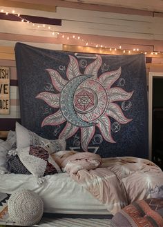 a large tapestry hanging on the wall above a bed with pillows, blankets and blankets