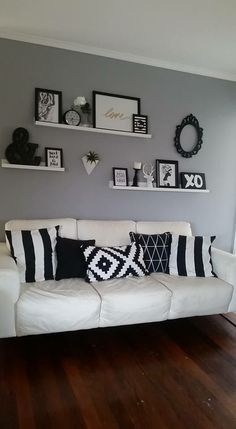 a white couch sitting on top of a hard wood floor next to a wall filled with pictures