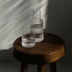 two glasses sitting on top of a wooden table next to a shadow cast by a wall