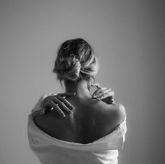 black and white photograph of woman in off shoulder dress holding her hand on her neck