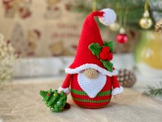 a crocheted christmas decoration with a santa clause hat and green holly leaves on top