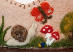 a close up of a stuffed animal in the grass with mushrooms and flowers on it