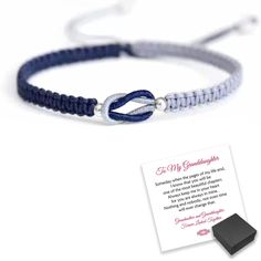 a blue and white cord bracelet with a card attached to the end, next to it's box