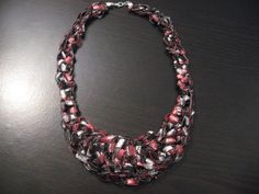 a black and red necklace on a table with a white bead around the neck