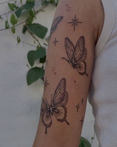 a woman's arm with two butterflies on it, and stars in the background