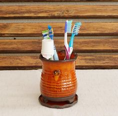 an orange cup with toothbrushes in it