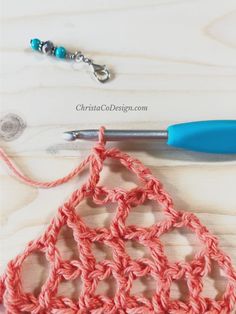 the crochet pattern is being worked on with a blue handled crochet hook