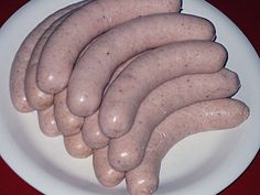 several sausages on a white plate sitting on a red table