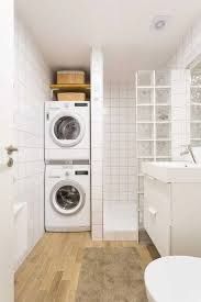 a washer and dryer in a white bathroom with wood flooring next to a toilet