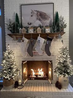 a fireplace decorated for christmas with stockings hanging from the mantel and trees on either side