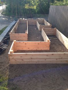 an outdoor garden area with raised wooden planters in the middle and dirt on the ground