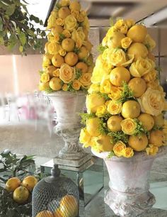 two large vases filled with yellow flowers and lemons