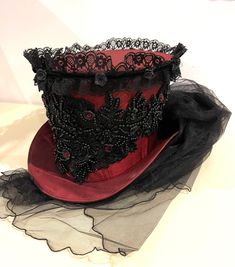 This is elegant Victorian gothic Hand made wine Maroon Top hat with black back beautifully hand crafted feathers and flowers black net bustle train. Top Hat with Black laces and 3D silk flowers and black pearls and dark red jewels and sequins hand stitched.  Please refer to the photos. This is stunning Victorian Steampunk Handmade top hat made with lots of love. It is very well made, this hat is made of a satin type of fabric and the inside of the hat is has a Black satin  lining. The front of t Gothic High Crown Costume Accessories For Costume Party, Elegant Halloween Costume Corset, Elegant Halloween Corset For Costume Party, Gothic Fitted High Crown Costume Accessories, Gothic Top Hat For Halloween Festival, Fitted Top Hat For Halloween Costume, Elegant Halloween Party Corset, Fitted Steampunk Top Hat For Halloween, Steampunk Fitted Top Hat For Halloween