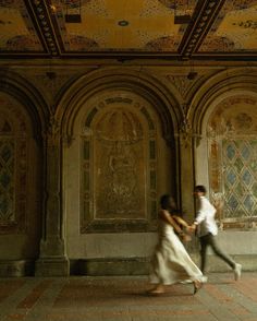 two people are walking in an old building