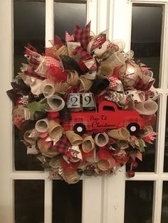 a red truck wreath is hanging on the front door, decorated with ribbon and ribbons