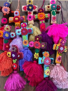 many different types of crocheted flowers and tassels on a wooden surface