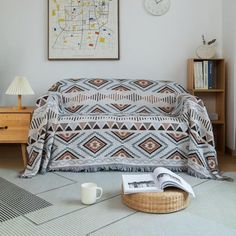 a living room with a couch covered in a blanket next to a coffee cup on the floor