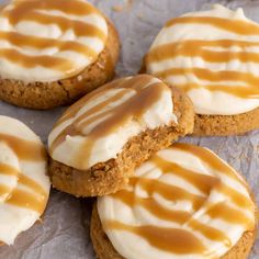 several cookies with frosting and caramel drizzled on them sitting on wax paper