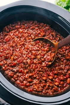 a wooden spoon in a slow cooker filled with chili