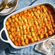 a casserole dish with cheese and sauce in it on a blue cloth next to silverware