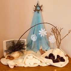 a wooden table topped with pine cones and other christmas decorations next to a blue curtain