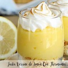 two glasses filled with lemon custard desserts on top of a wooden table