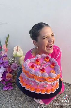 a woman sitting in front of a pink cake