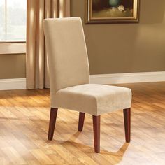 a dining room chair with a beige cover on it's back and wooden legs