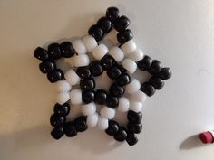 several black and white beads are arranged in the shape of a star on a wall