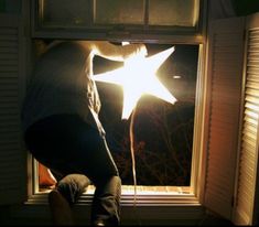 a person standing in front of a window with the sun shining through it and holding onto a string