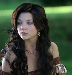 a woman with long black hair wearing a brown dress