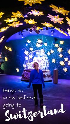 a woman standing in front of a snow globe at night with the words things to know before going to switzerland