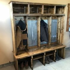 a wooden bench with two coats hanging on it's sides and some boots next to it