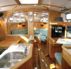 the inside of a boat with wood flooring and green couches on it's sides