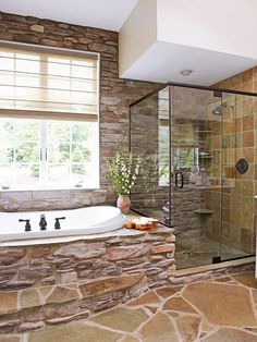 a bathroom with stone walls and a large tub next to a walk - in shower