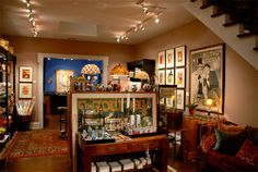 a living room filled with furniture and lots of framed pictures on the wall next to a stair case