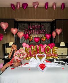 a woman sitting on top of a bed in front of balloons that spell out happy birthday