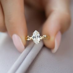 a close up of a person's hand holding a ring with a diamond on it