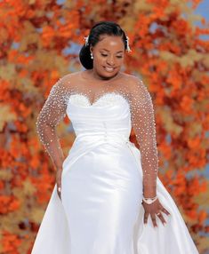 a woman in a white wedding dress standing next to an orange tree