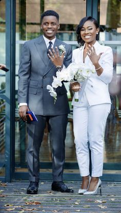 a man and woman standing next to each other in front of a glass door with flowers on it