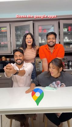 four people sitting at a table with google logo on it and the caption guess the google apps