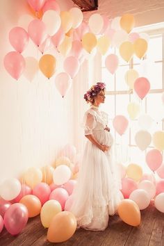 a pregnant woman standing in front of balloons