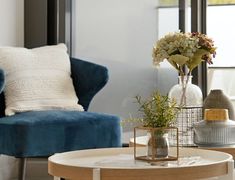 a living room filled with furniture and flowers on top of a coffee table in front of a window