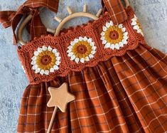 an orange and white dress with sunflowers is hanging on a wooden hanger