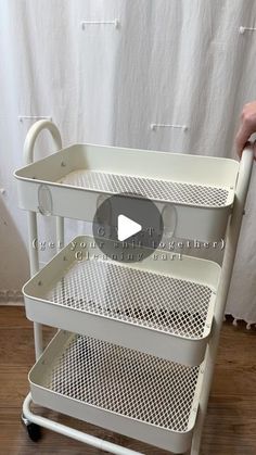 a person is pushing a cart with three shelves on it and the wheels are white