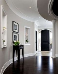 a black and white hallway with framed pictures on the wall next to a wooden floor