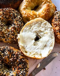 an assortment of bagels and doughnuts on a plate with a knife next to them