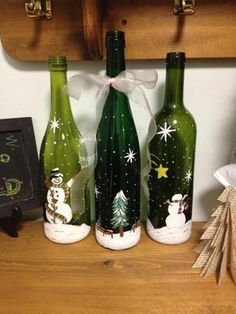 three wine bottles decorated with snowmen and christmas trees are sitting on a shelf next to a small tree